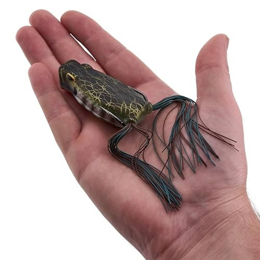 Soft frog lure resting on an open palm, dark camo with yellow web pattern and skirt