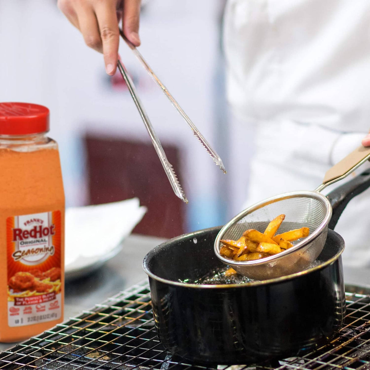 Seasoning bottle next to black skillet with a spoonful of sauced food