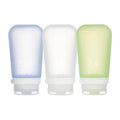Three refillable silicone travel bottles in blue, white, and light green with snap caps