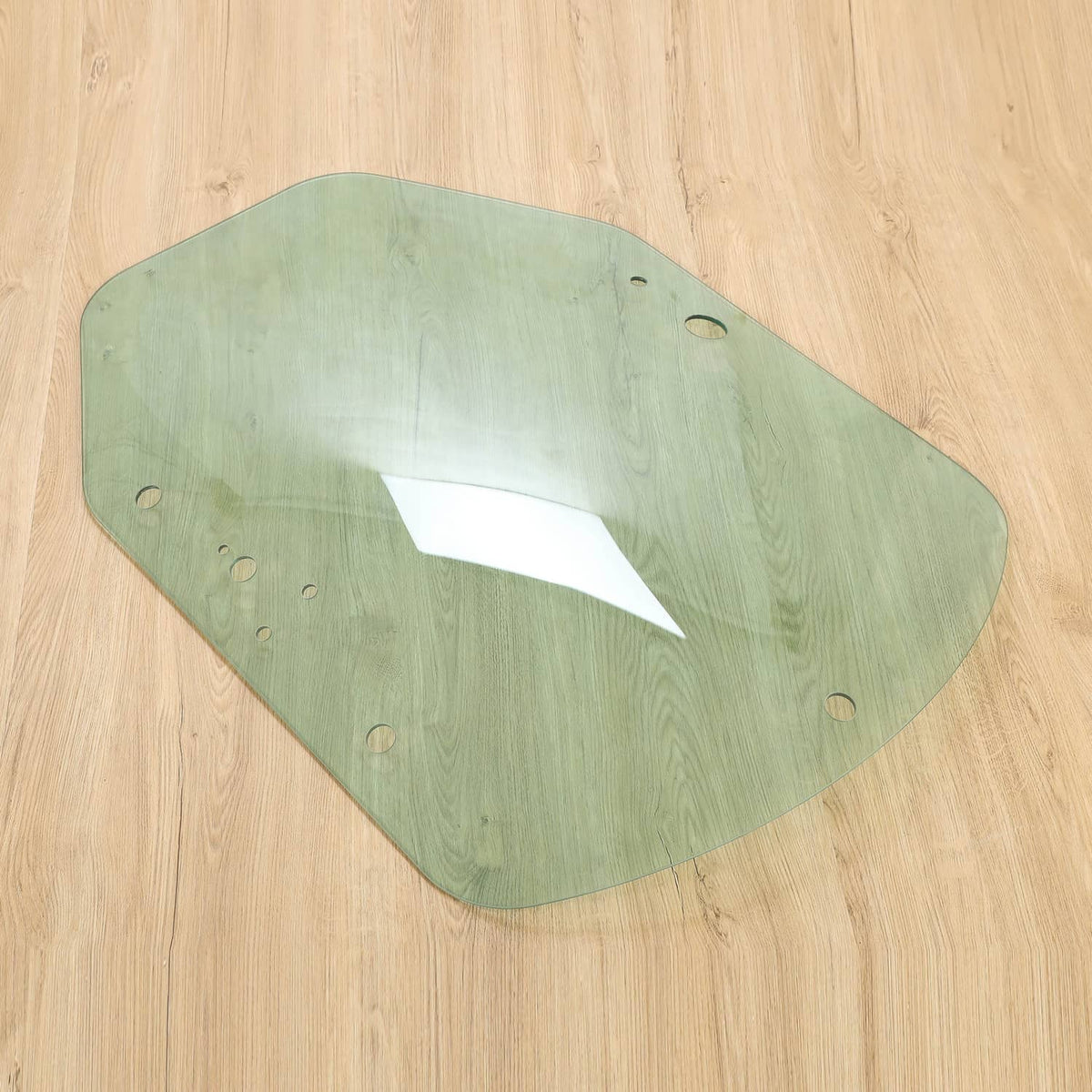 Skid steer cab door glass panel, light green tinted, mounting holes along edges