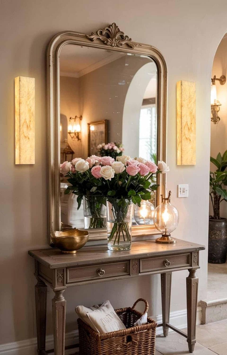 Two rectangular marble wall sconces flanking a bathroom vanity mirror with warm glow