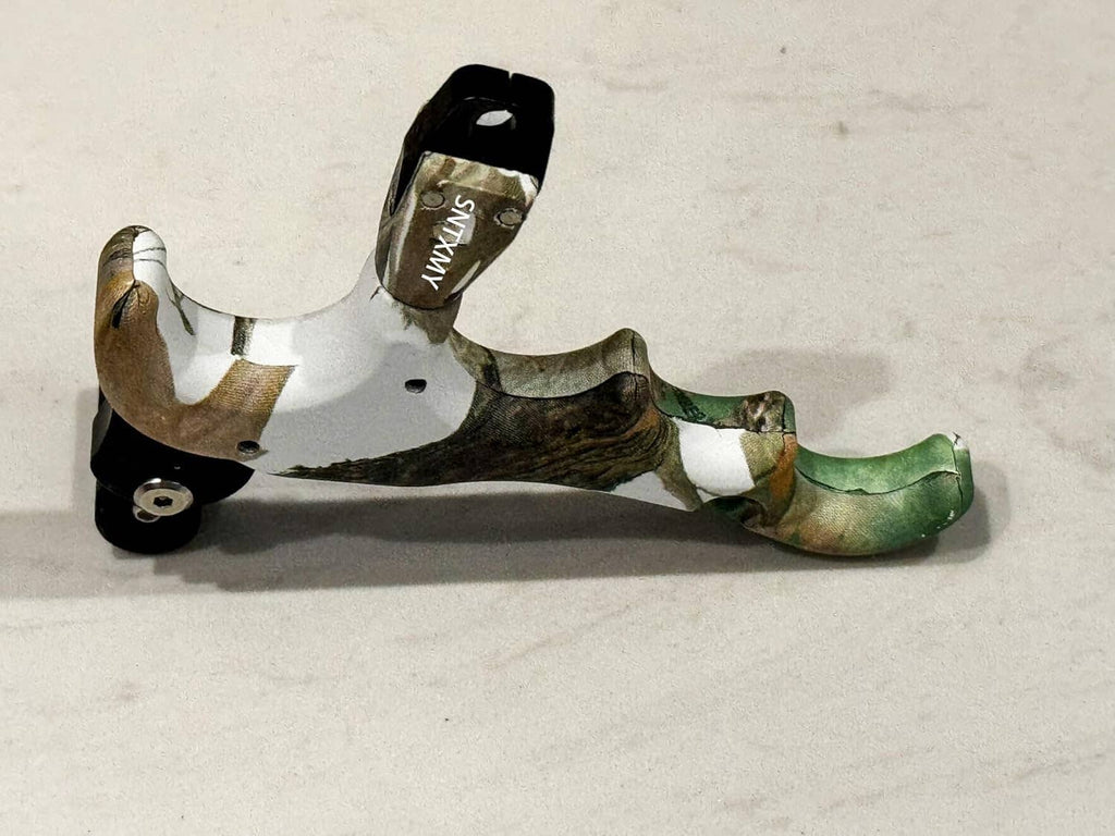 Camouflage thumb bow release with black trigger housing and extended metal rod.