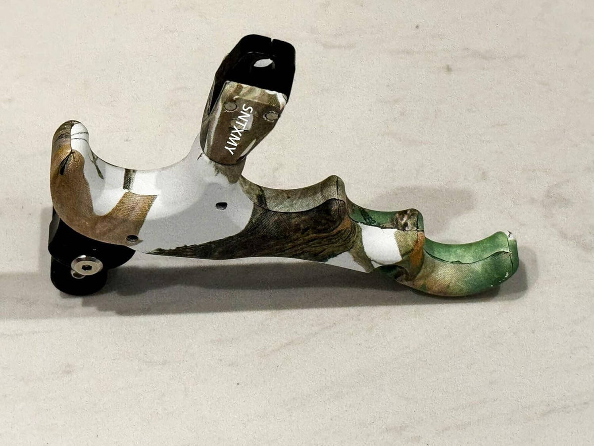 Camouflage thumb bow release with black trigger housing and extended metal rod.