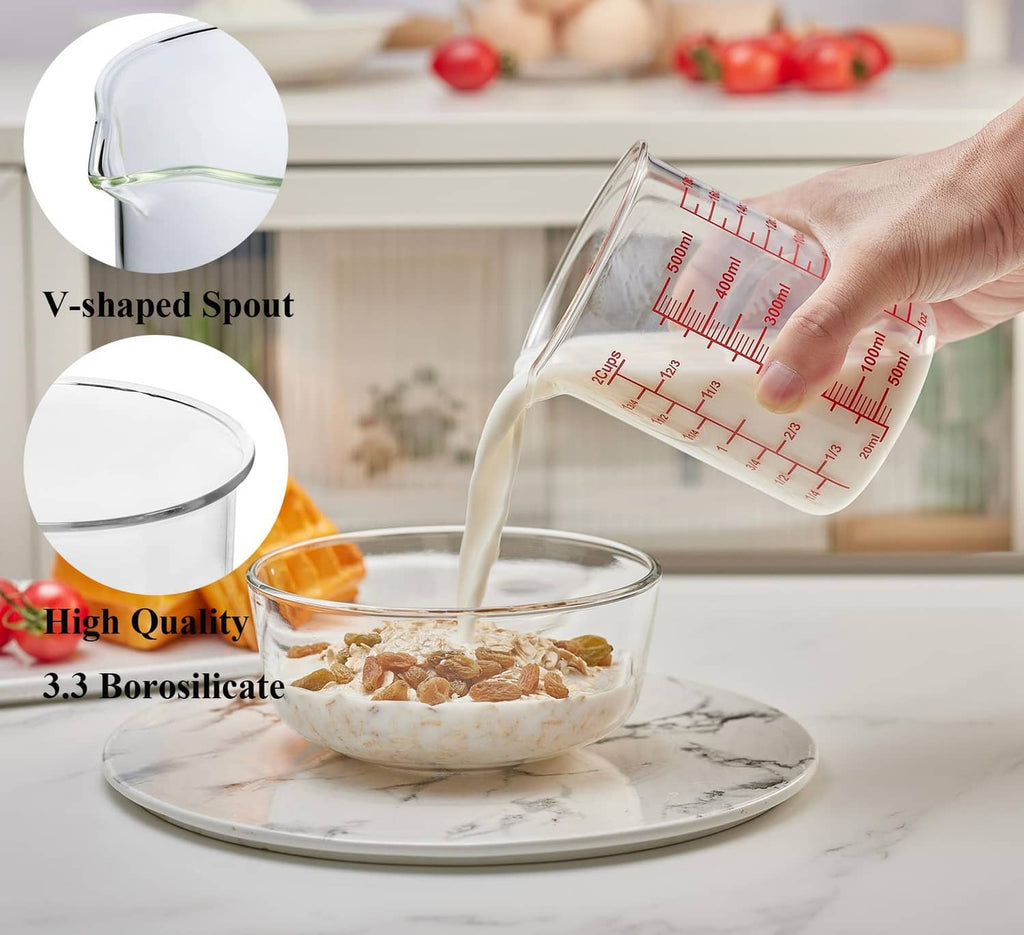 Clear glass measuring cup with V-shaped spout, red scale markings, being poured from 500 ml