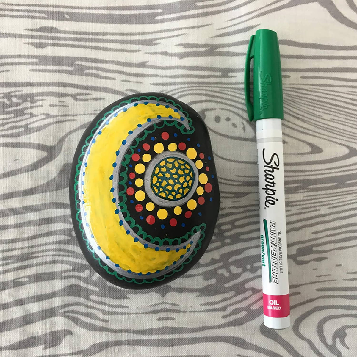 White Sharpie oil-based paint marker with green cap, medium point, on patterned surface