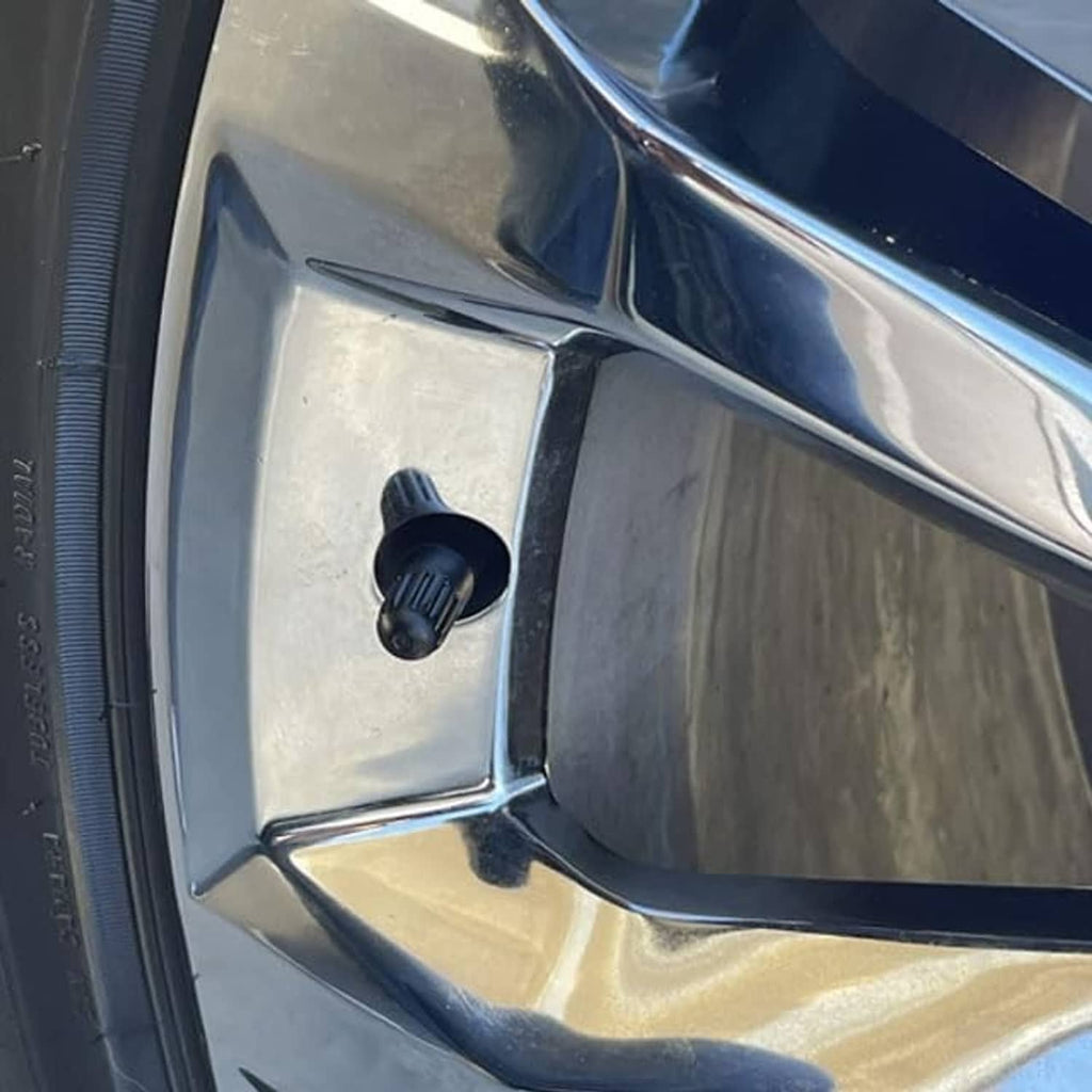 Black long tire valve stem cap installed on a metal alloy wheel
