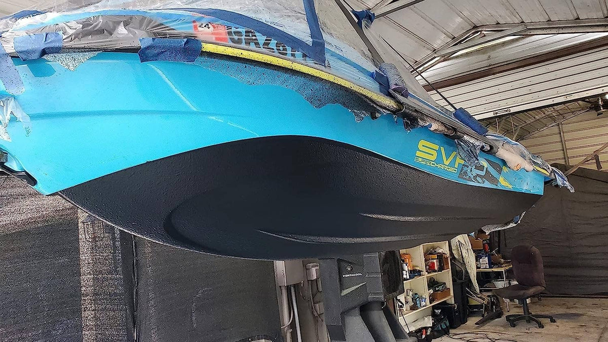 Blue and black jet ski hull underside with dark trim, in a workshop