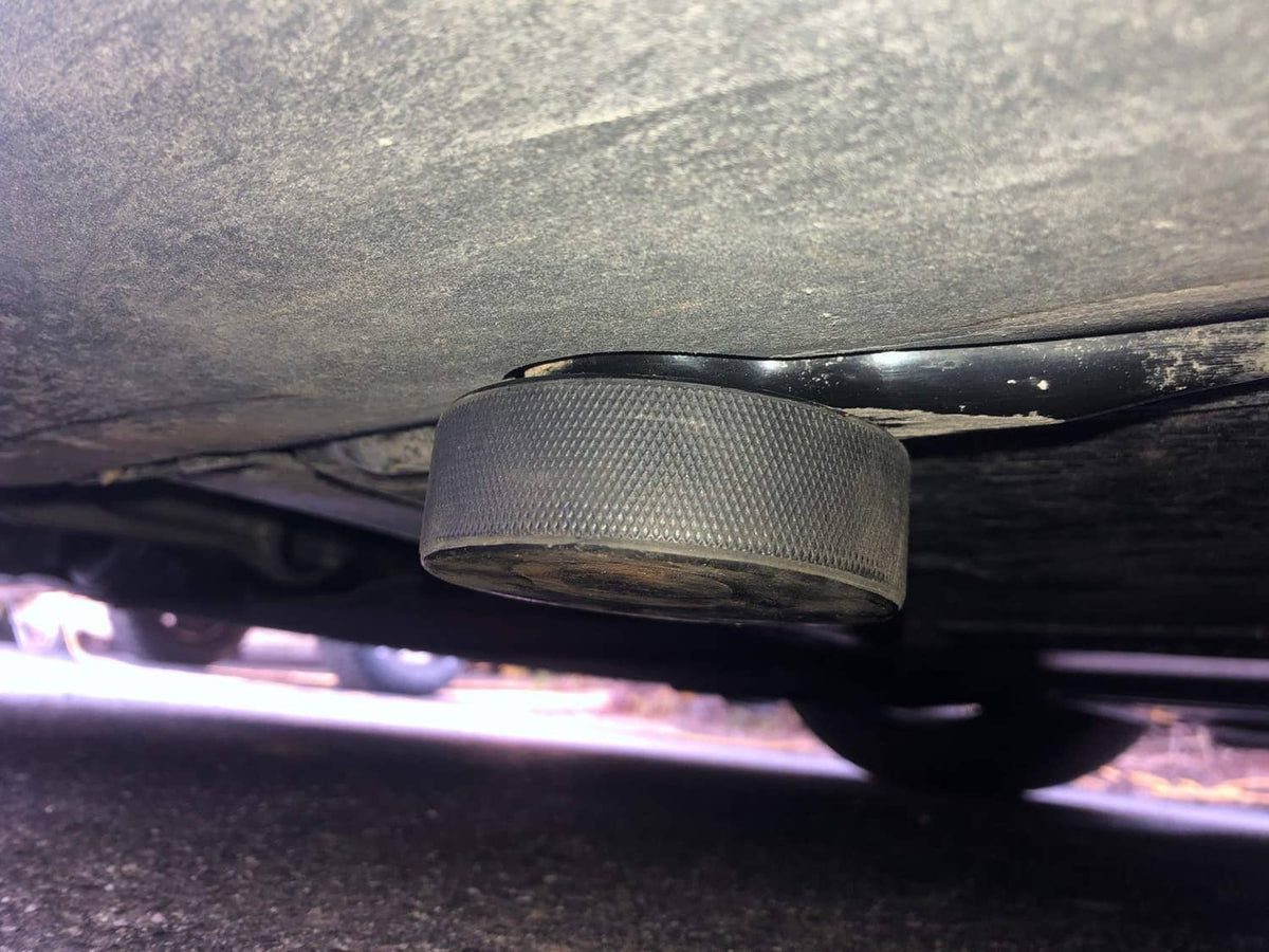 Black lifting jack pad under vehicle rocker panel, textured top
