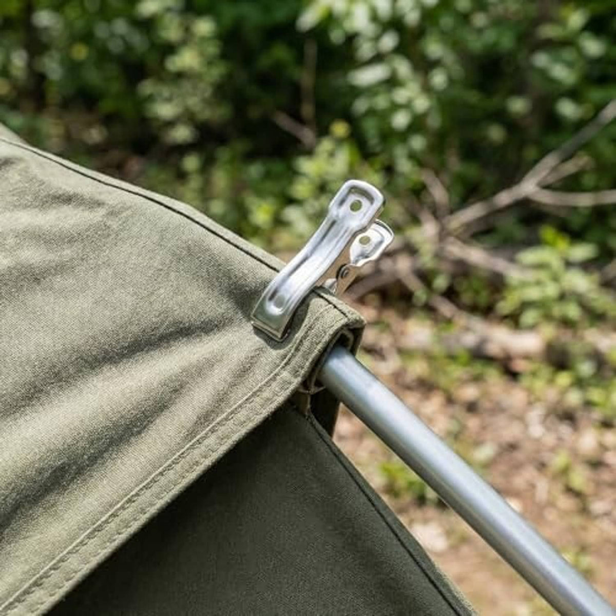 Stainless steel clamp securing green fabric over a metal pole outdoors