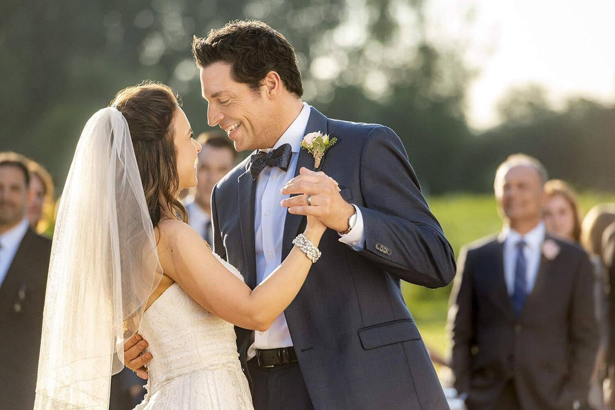 Film still of a wedding couple smiling during their ceremony in a garden setting