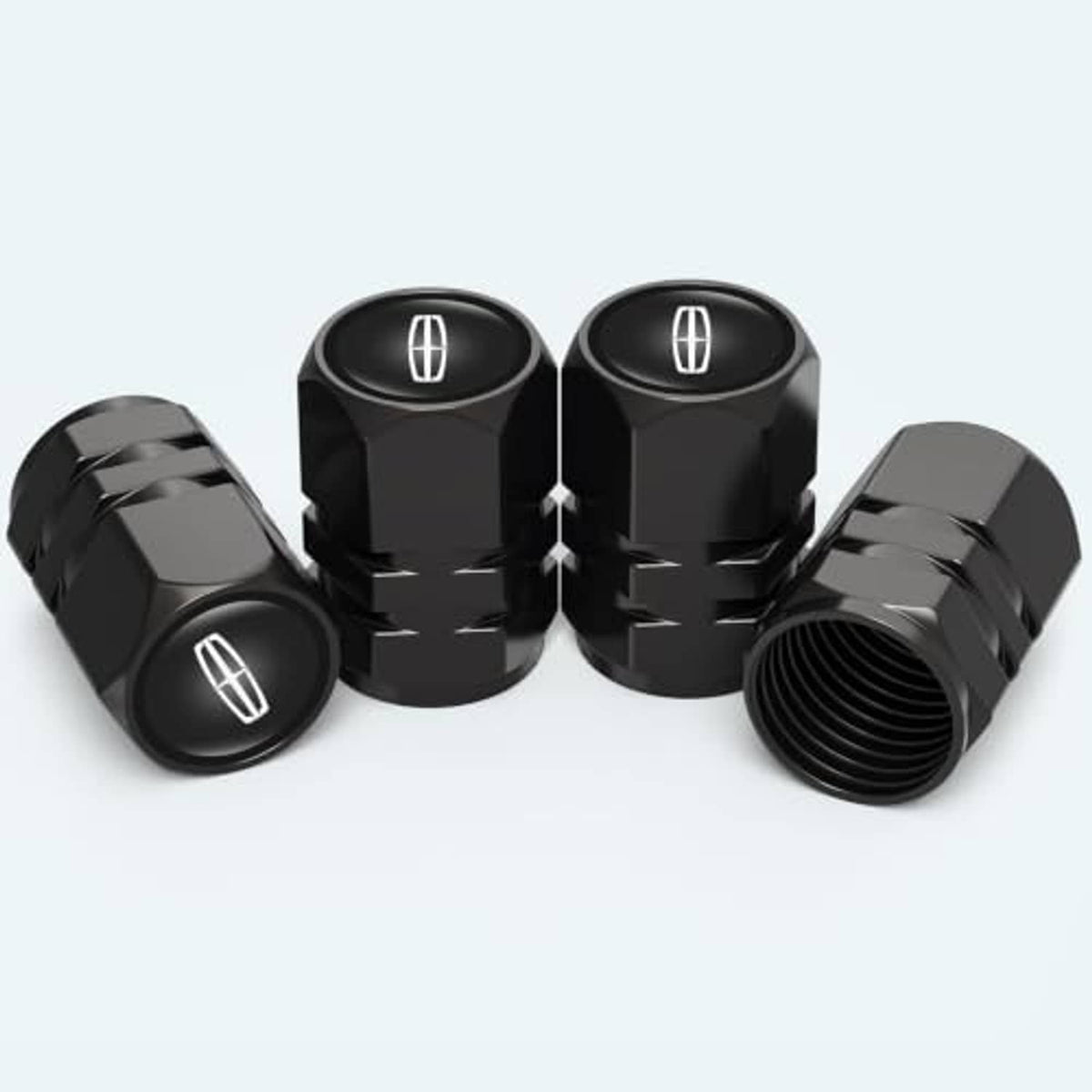 Four black tire valve stem caps, one open with threads, oval tire symbol