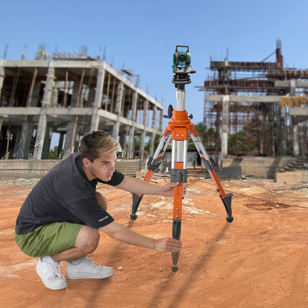 Orange laser level tripod stand with mounted instrument on three legs at a construction site