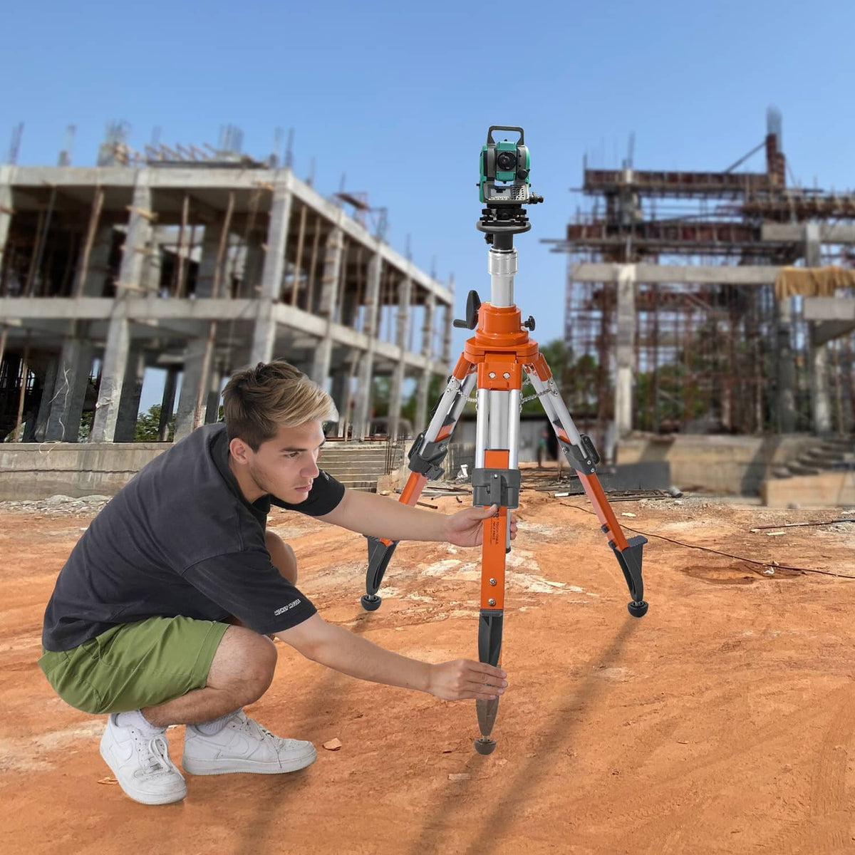Orange laser level tripod stand with mounted instrument on three legs at a construction site