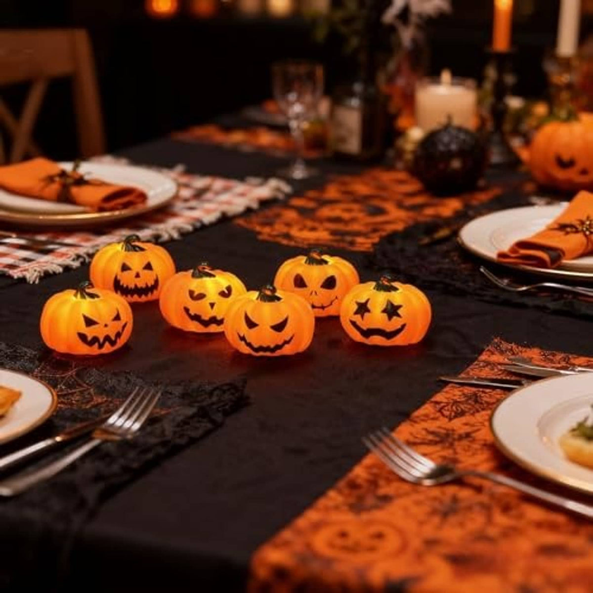 Halloween pumpkin tea lights scattered on a table with glowing jack-o’-lantern faces