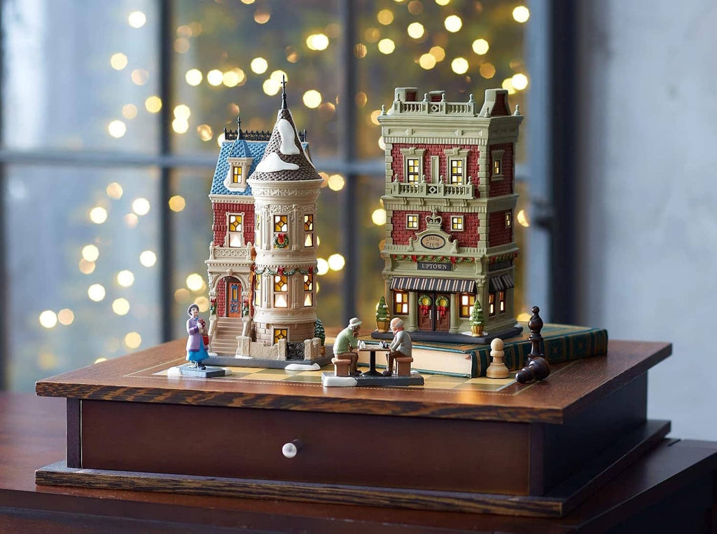 Winter village chess diorama figurines and tall buildings arranged on a wooden display base.