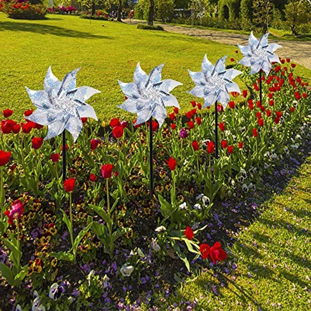 Reflective silver pinwheels with black stakes and glitter blades, in a flower bed