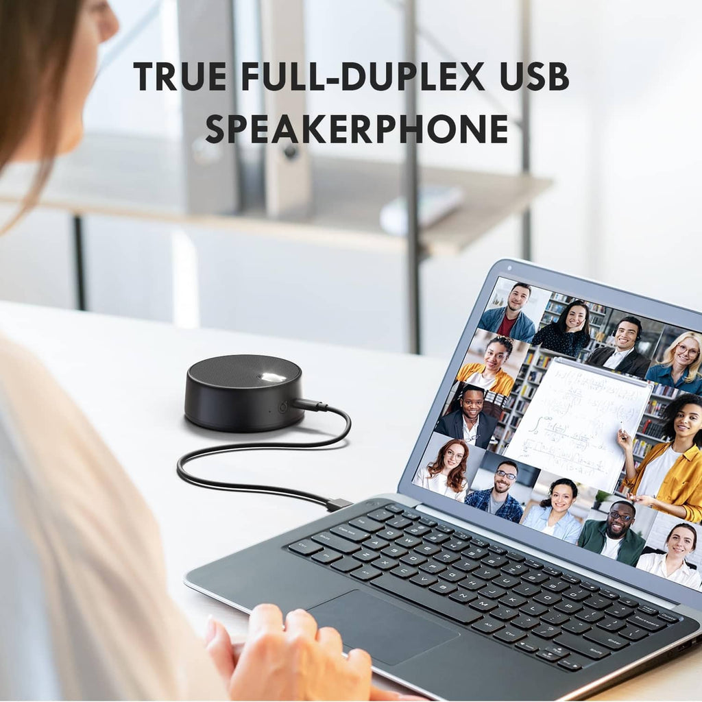 Small black USB speaker with microphone next to laptop, USB cable attached
