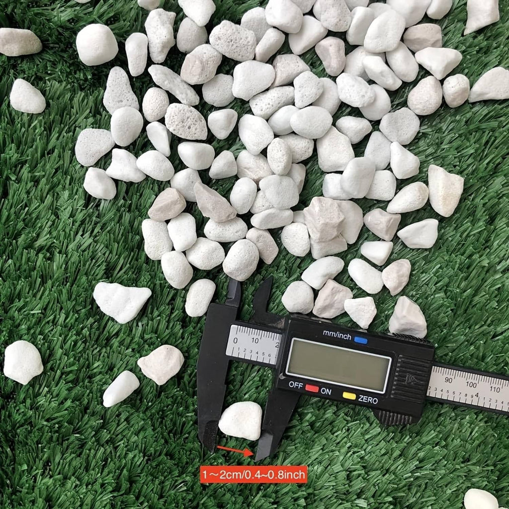 Loose white chunky perlite stones with ruler for size, shown on grass surface