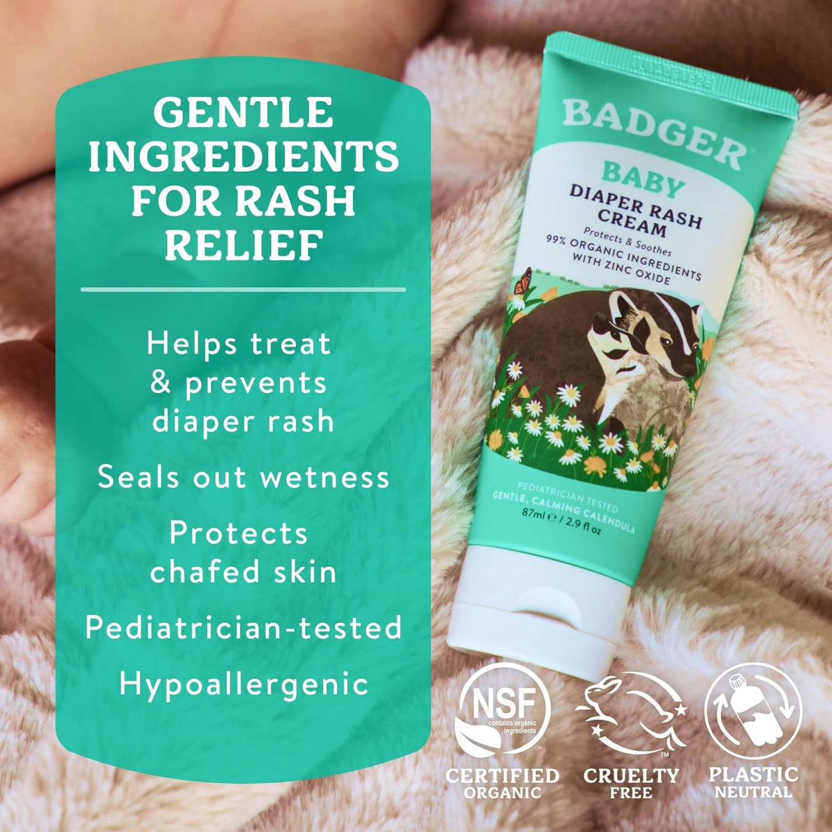 BADGER Baby diaper rash cream tube held in hand on soft blanket, teal label