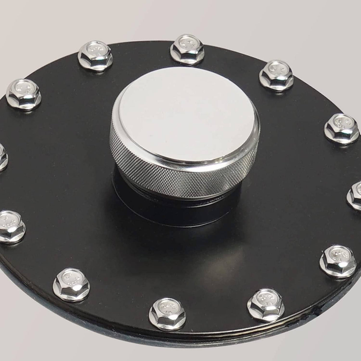 Round fuel cap on black mounting plate with hex bolts
