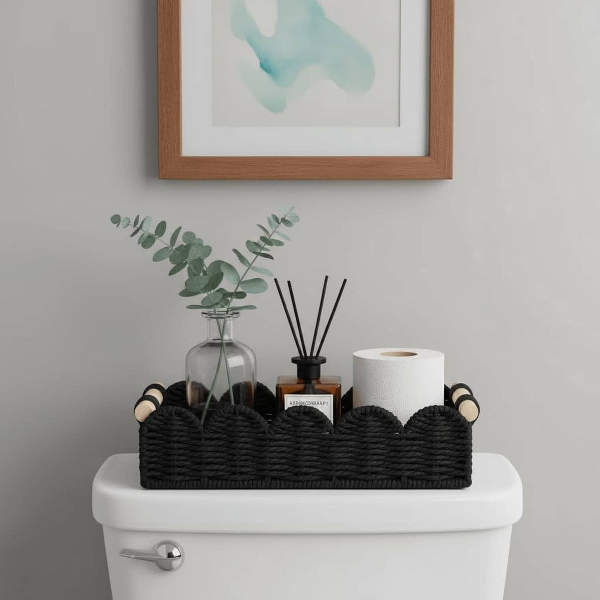 Black woven storage basket with wood-capped handles holding toiletries and a paper roll