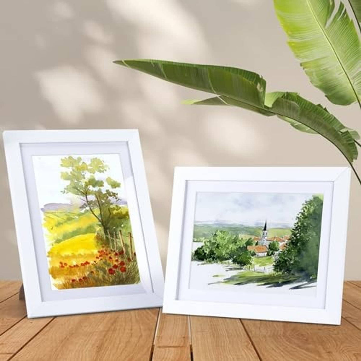 Two white picture frames with white borders, each displaying artwork print