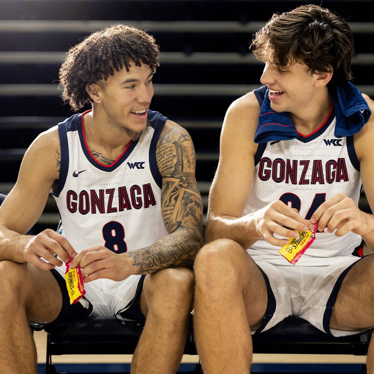 Two athletes seated with Honey Stinger organic fruit smoothie energy gel packets