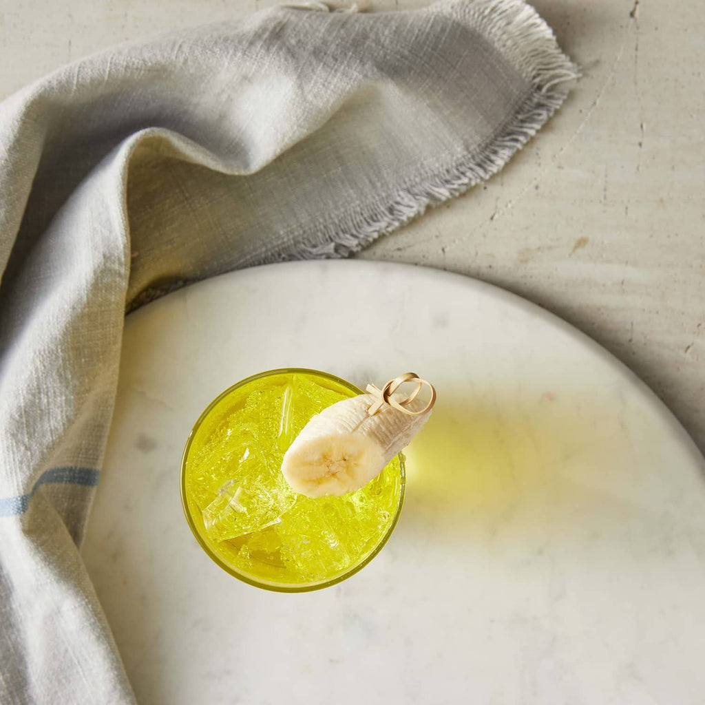 Yellow banana syrup in shallow cup with banana slice garnish