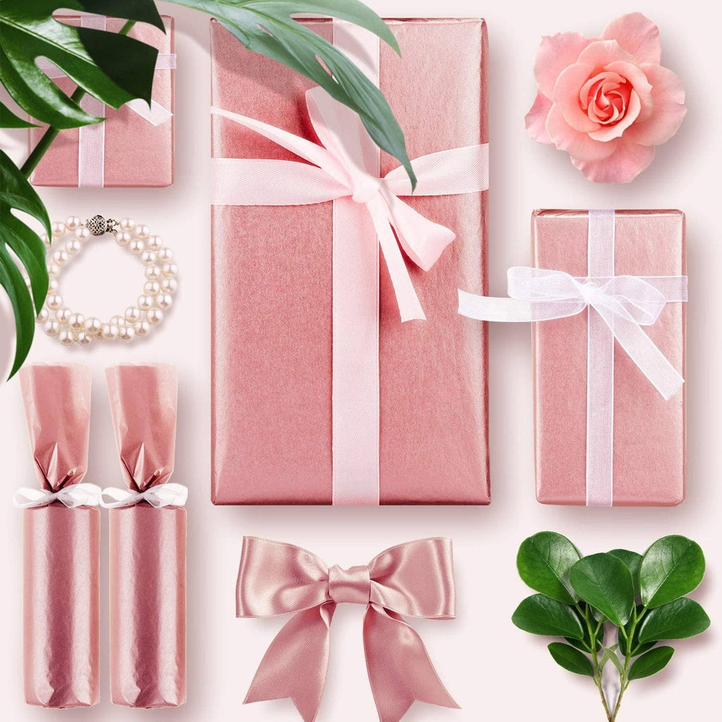Rose gold metallic tissue paper sheets wrapping gift boxes with white ribbon bows