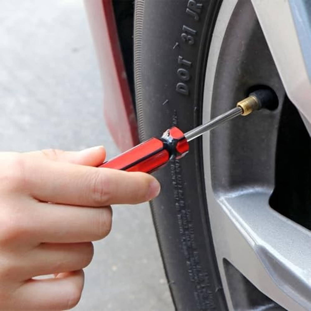 Hand holding a red-and-black valve core remover tool inserting into tire valve