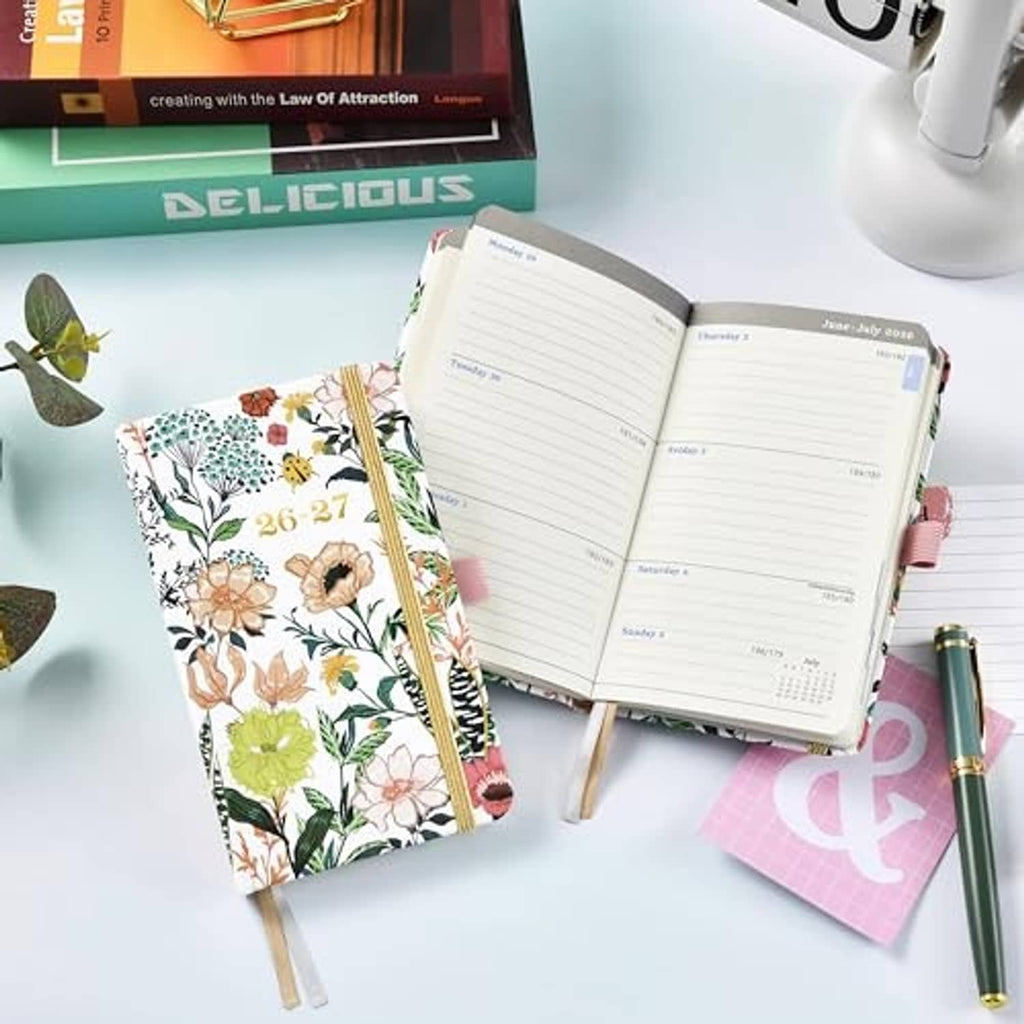 Pocket planner calendar open to lined pages with a floral cover and gold spine