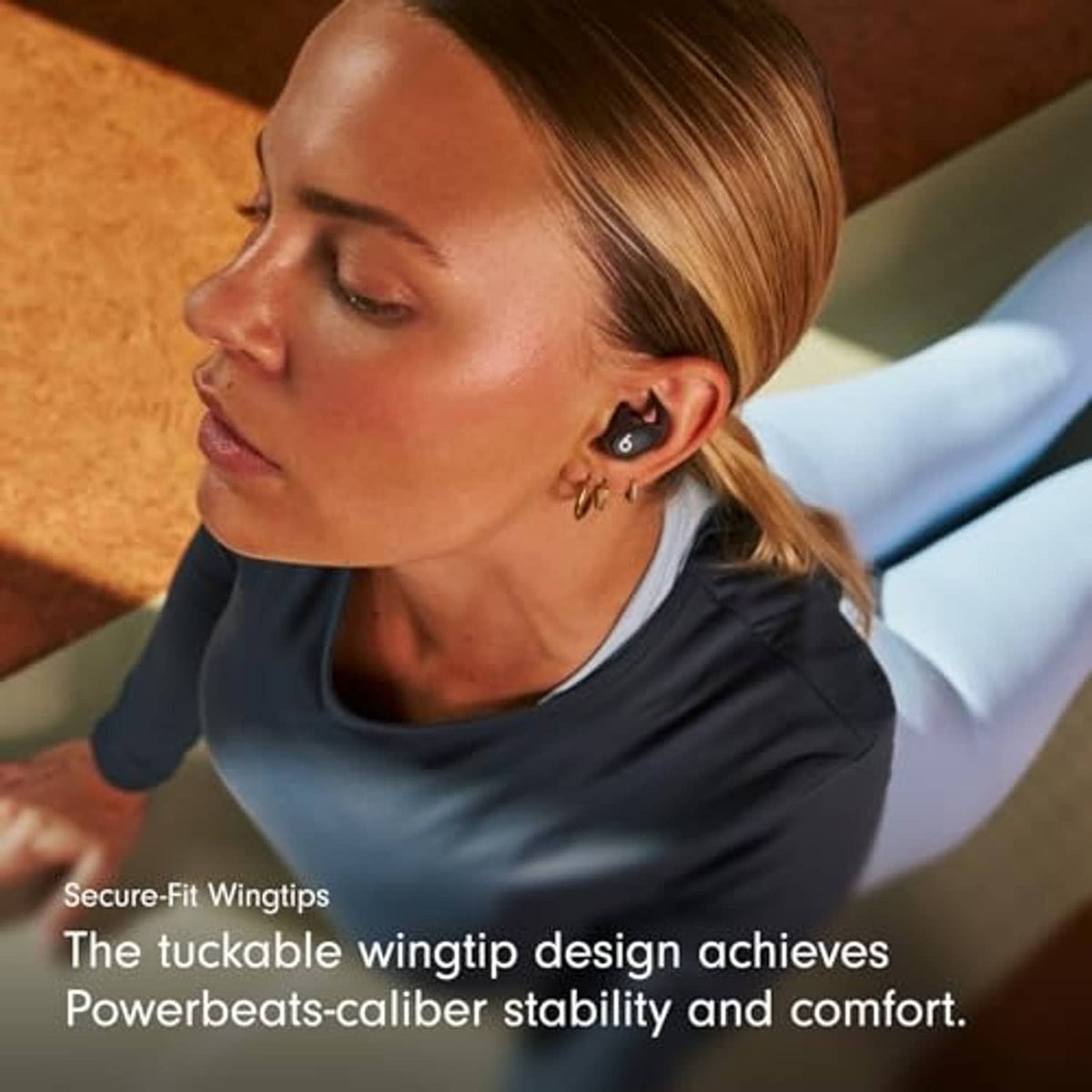 Wireless workout earbuds in ears with secure-fit wingtip design on dark earbuds