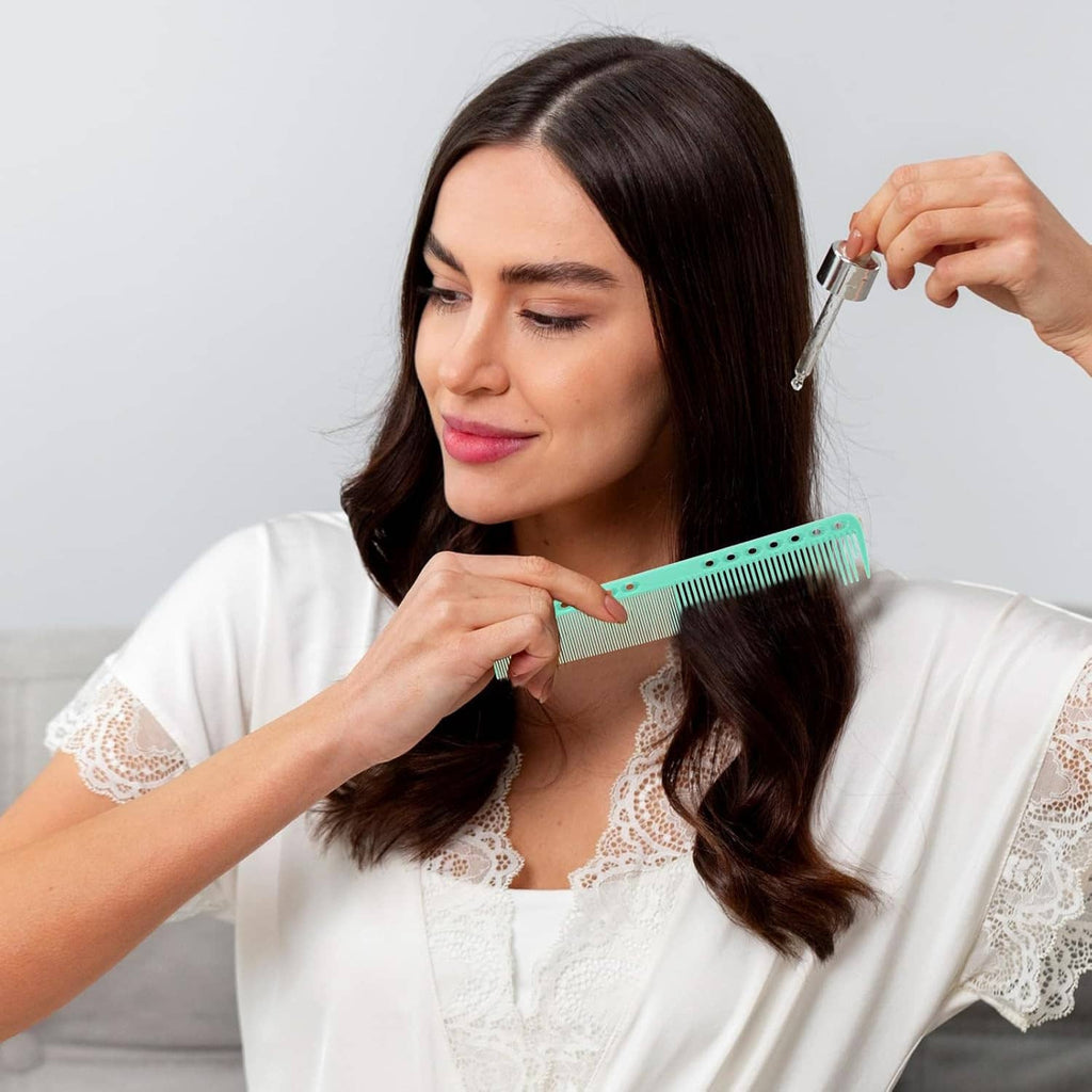 Teal fine-tooth cutting comb held near hair, narrow handle with side holes