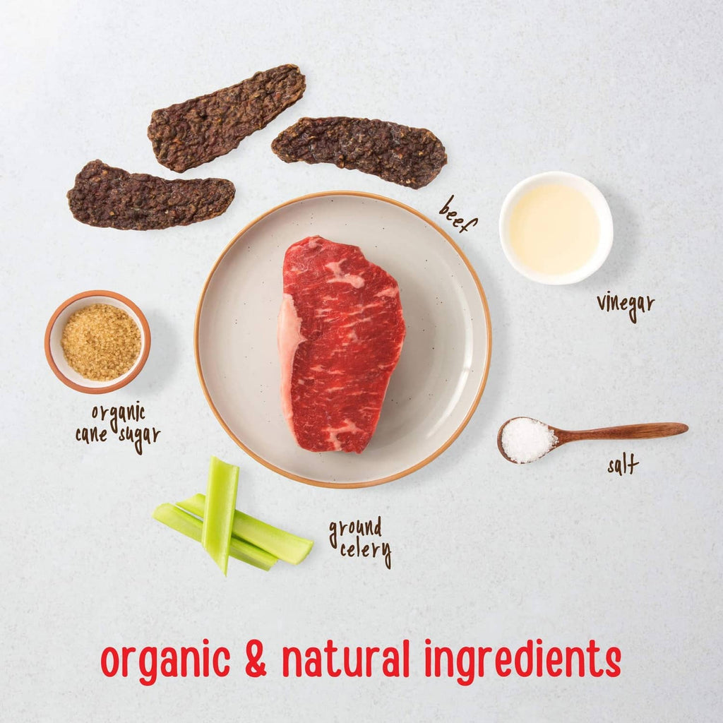Sliced dark beef jerky dog treats on plate with small ingredient bowls