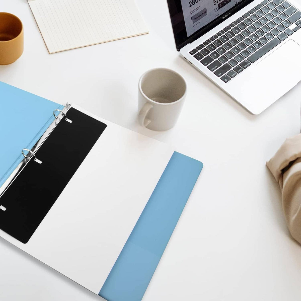 Black and blue binder sheet lifter plates with metal rings on a desk