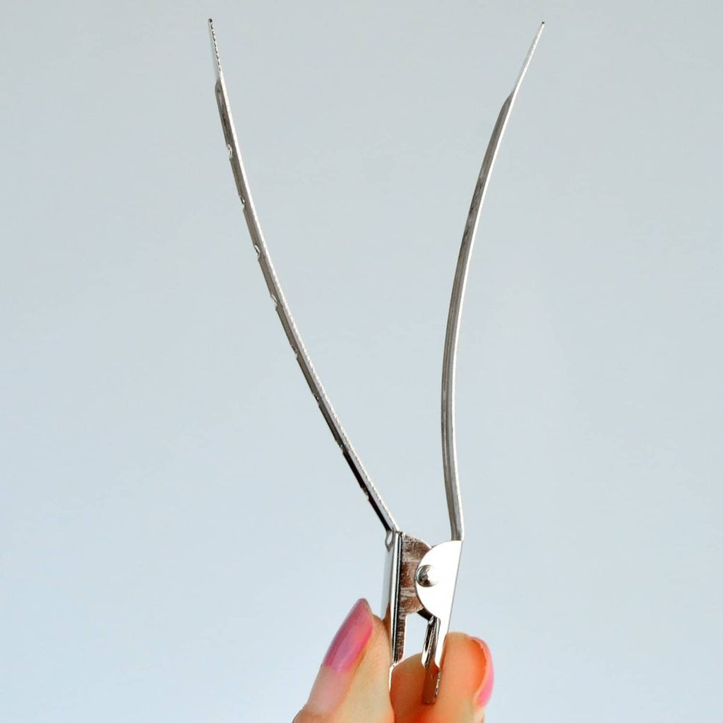 Hand holding a metal duck-bill clip with pivot hinge and fastening teeth