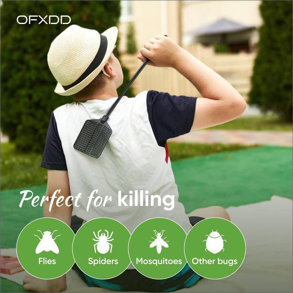 Black rubber fly swatter with perforated head on long handle in outdoor setting