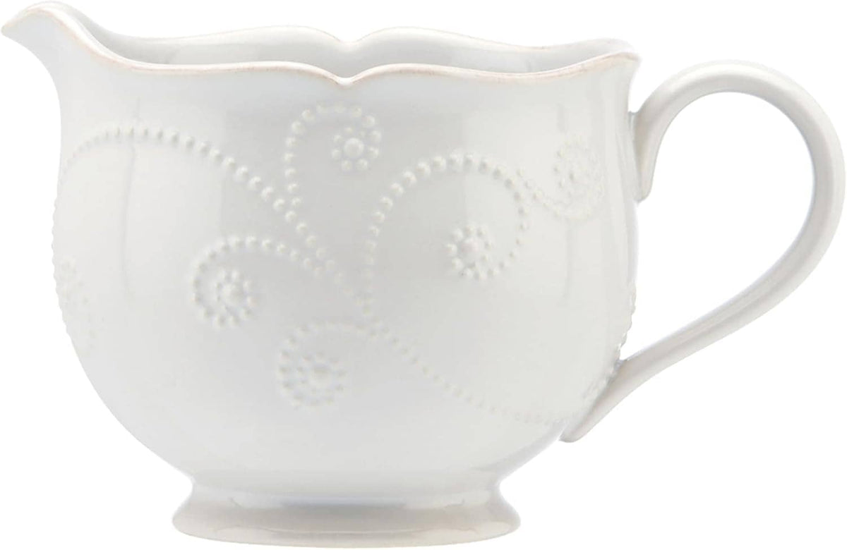White ceramic sauce pitcher, embossed circular floral dots and scalloped edge