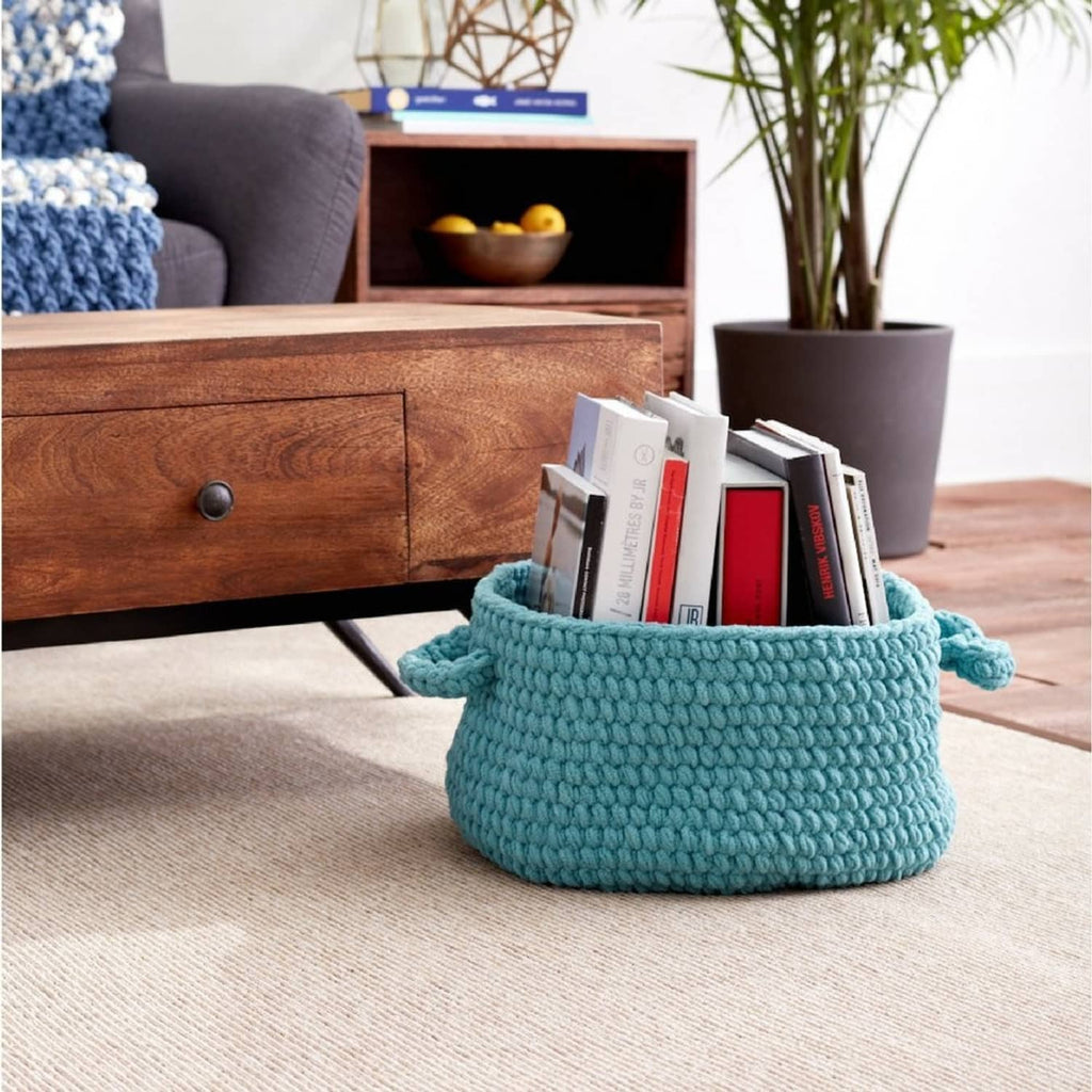 Light teal chunky knit yarn basket holding books and papers