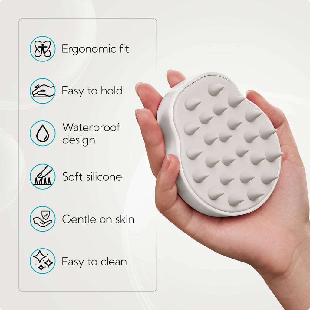 White silicone scalp massager brush with raised nub grips, held in a hand.