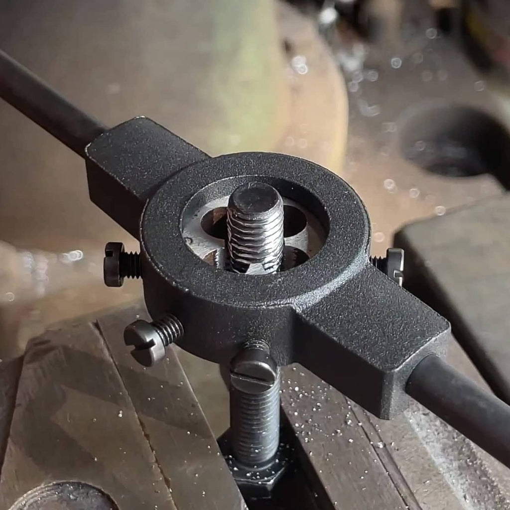 Threading die setup on metal workpiece, held in a clamp with visible cutting teeth