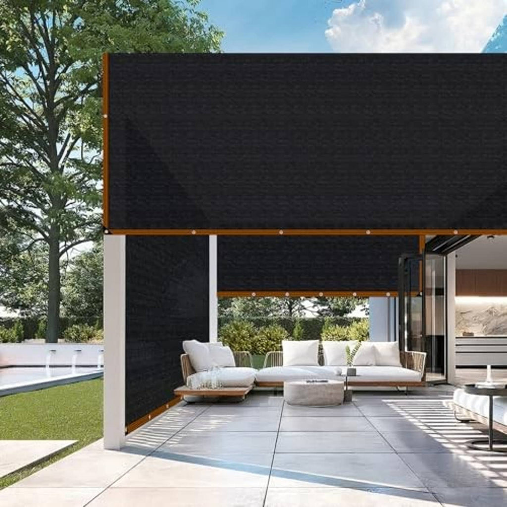 Black rectangular mesh shade cloth installed above patio seating under a frame.