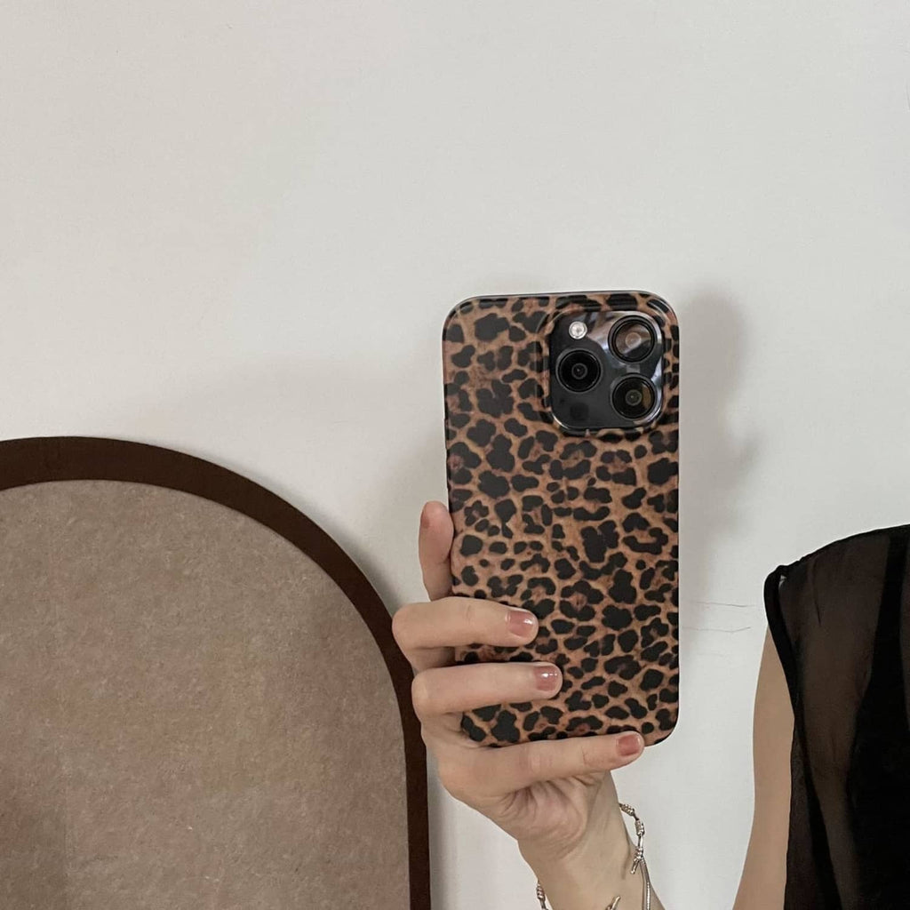 Brown leopard print phone case with camera cluster, held in a hand