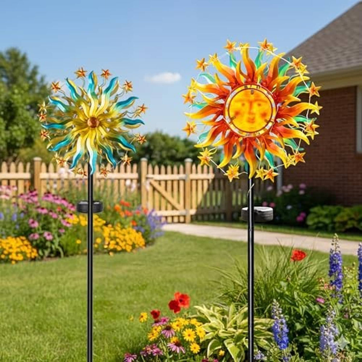 Two solar sun wind spinners with colorful rays displayed among flowers and grass.