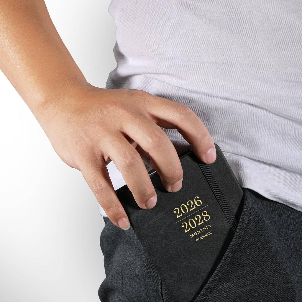 Dark pocket calendar with “2026–2028 Monthly Planner” cover, hand holding front elastic pocket