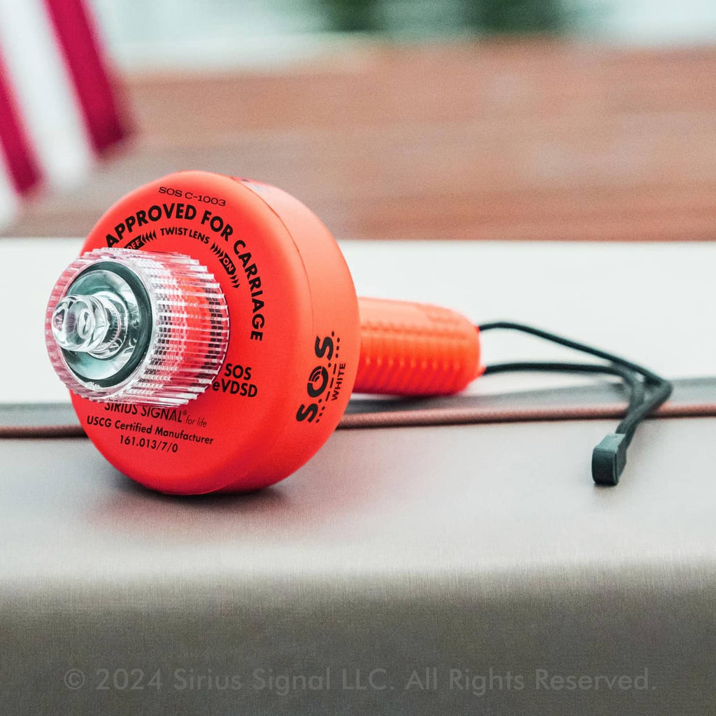 Red SOS LED distress flare lying on a surface with black lanyard attached