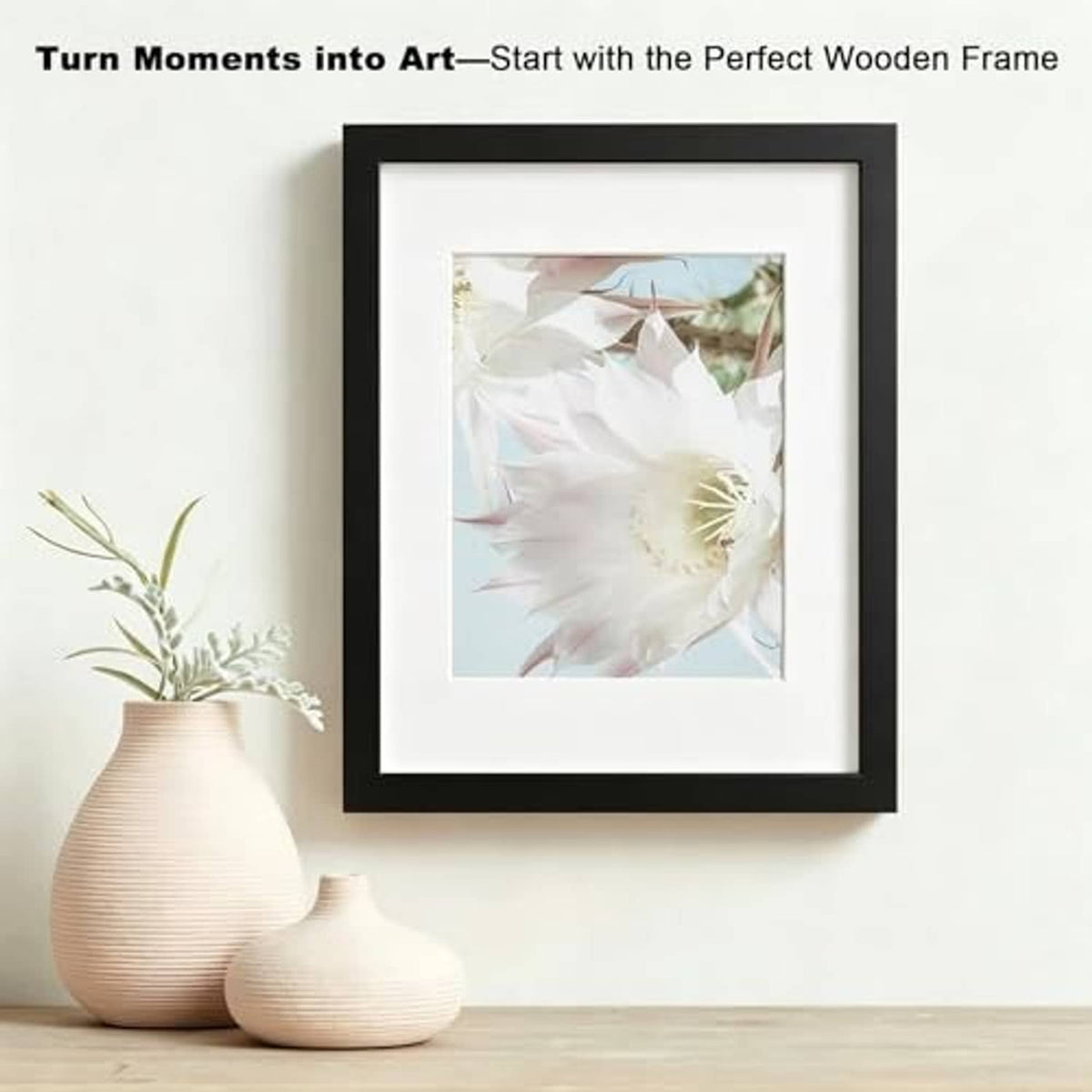 Black wooden picture frame with clear glass, holding a white flower print