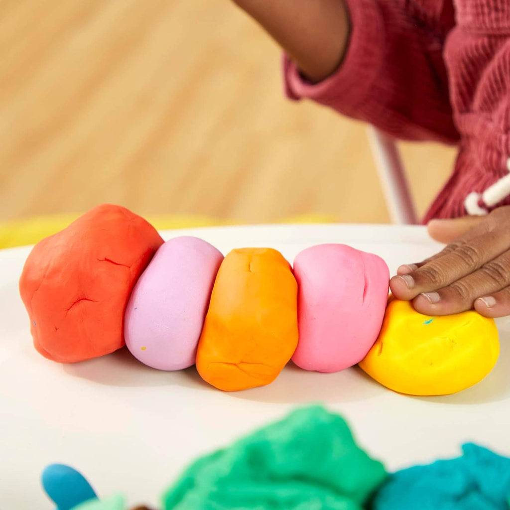 Assorted Play-Doh clay pieces shaped into colorful logs with hands
