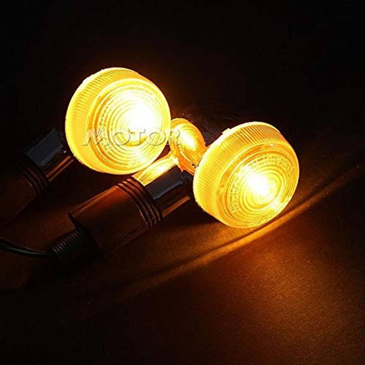 Pair of motorcycle turn signal lights glowing amber, chrome housings with black mounts