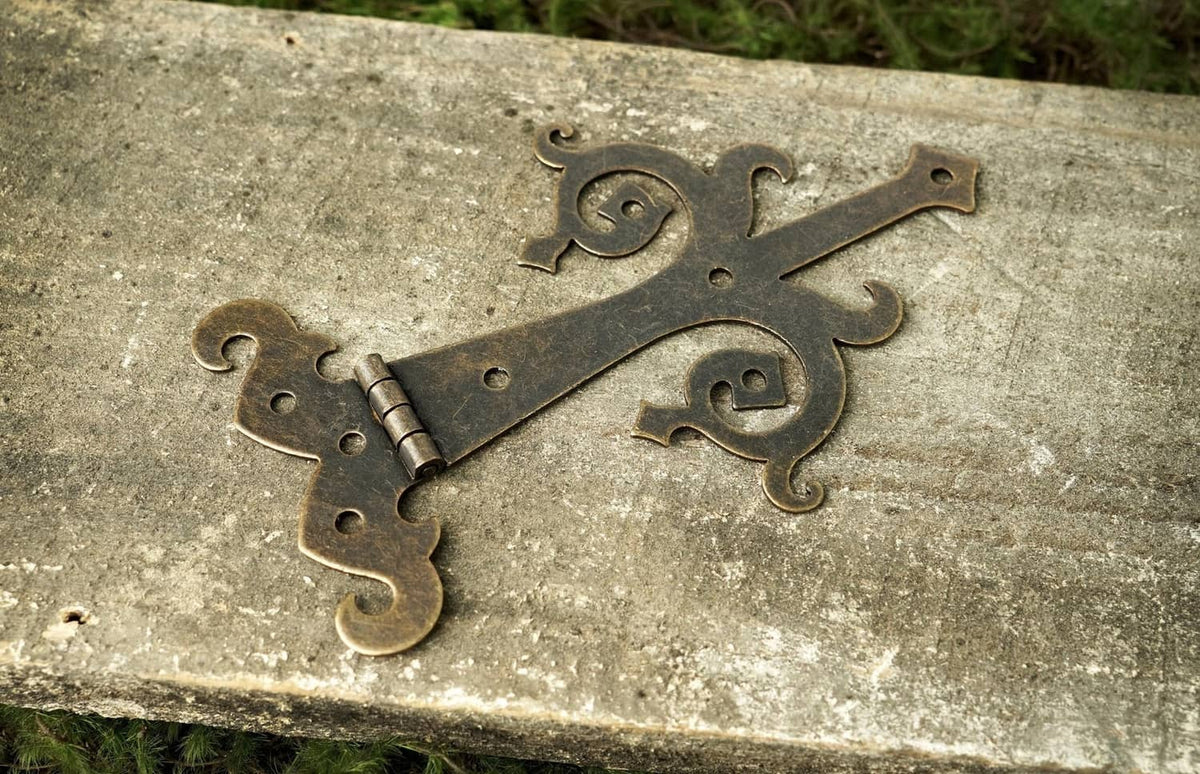 Bronze strap hinge with curled scroll ornament and two pin barrels